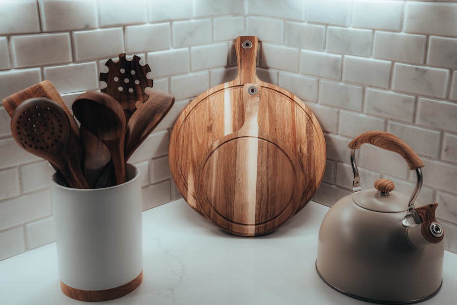 Cozy kitchen corner with wooden utensils, cutting board, and tea kettle against a tiled wall.